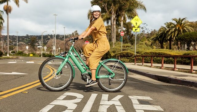 Urban E-Bike mit Person und Palmen im Hintergrund